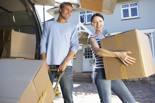 Removalists carrying furniture through a narrow hallway in a local home